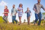 people running on grassfield under blue skies at daytime