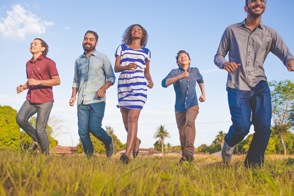 people running on grassfield under blue skies at daytime