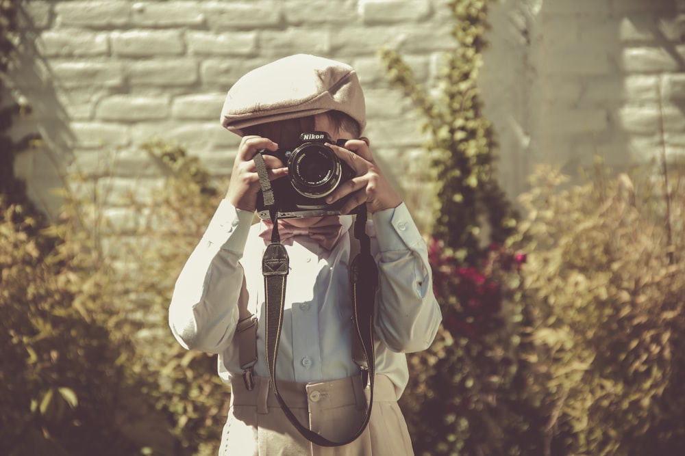 niño sosteniendo una cámara DSLR negra