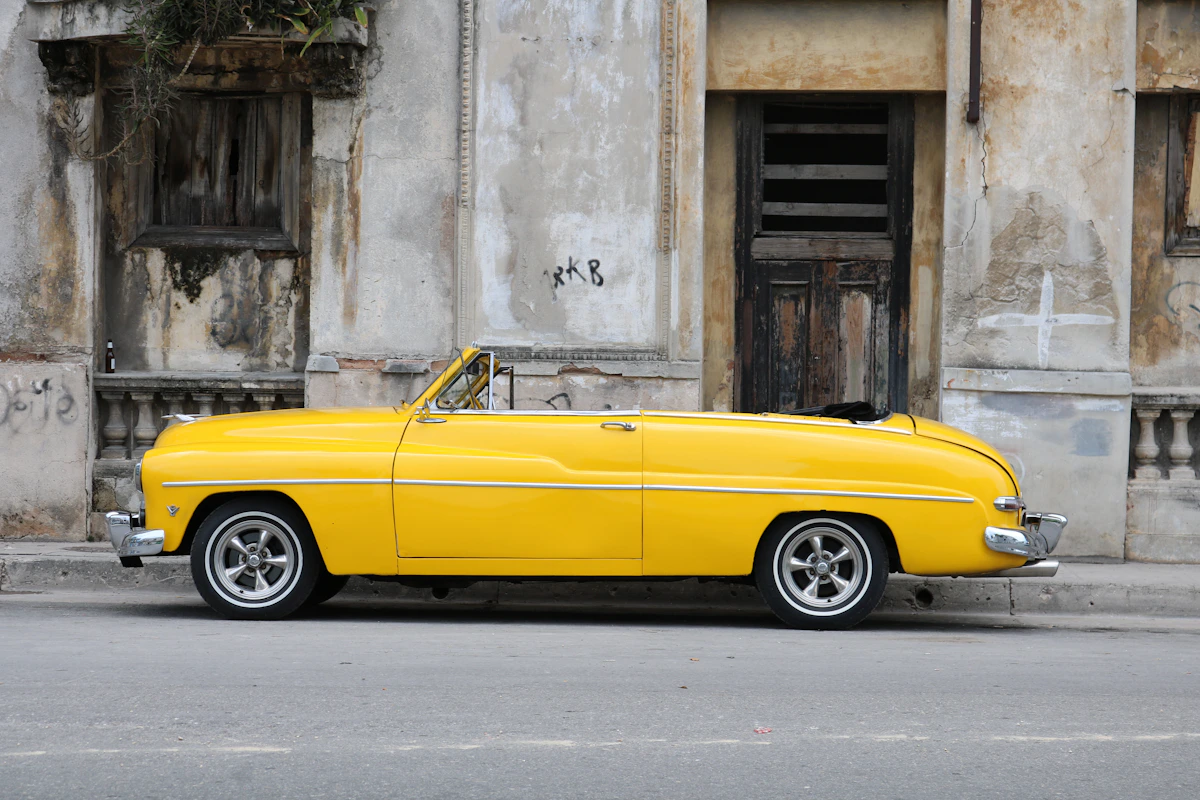 Classic convertible car with the top up driving along a coastal road