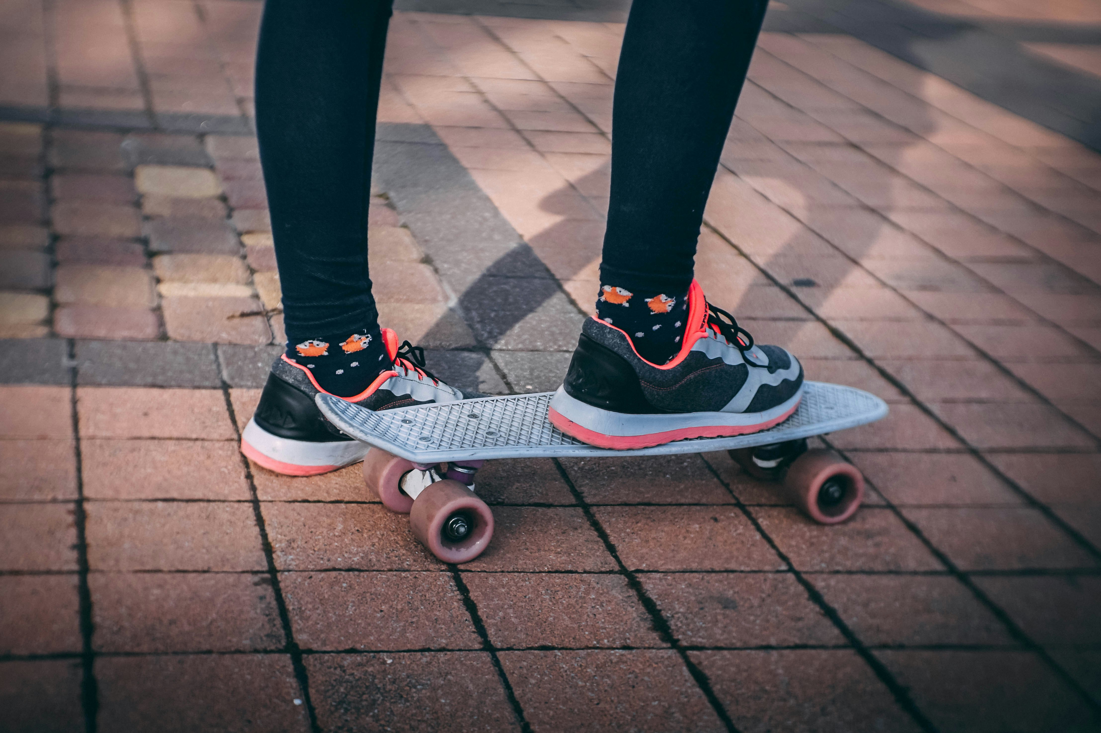 person wearing running shoes using penny board