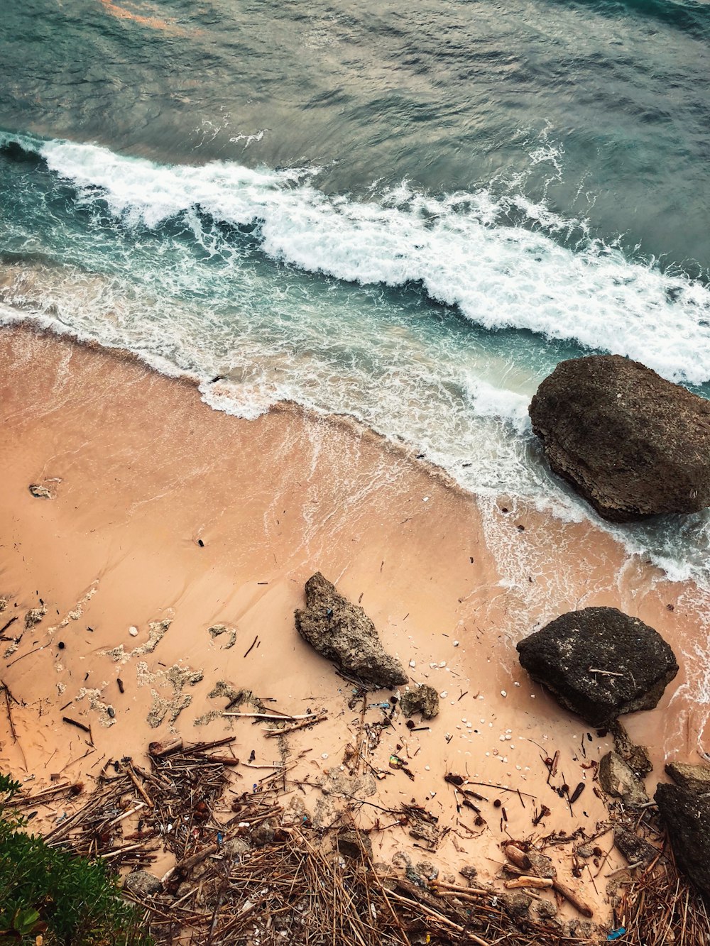 昼間の海辺の海岸の岩や木の棒の空撮写真
