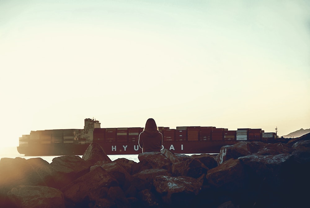 person sitting on rock fronting rain