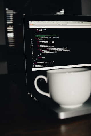 photo of white ceramic teacup on turned on MacBook Pro