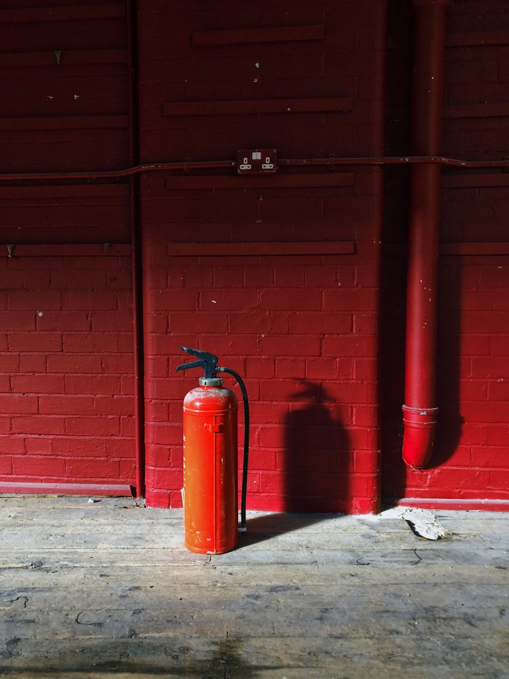 Extintor de incendios rojo cerca de la pared roja