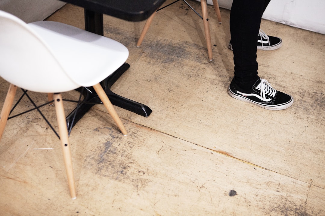 person standing on brown floor near table and chair