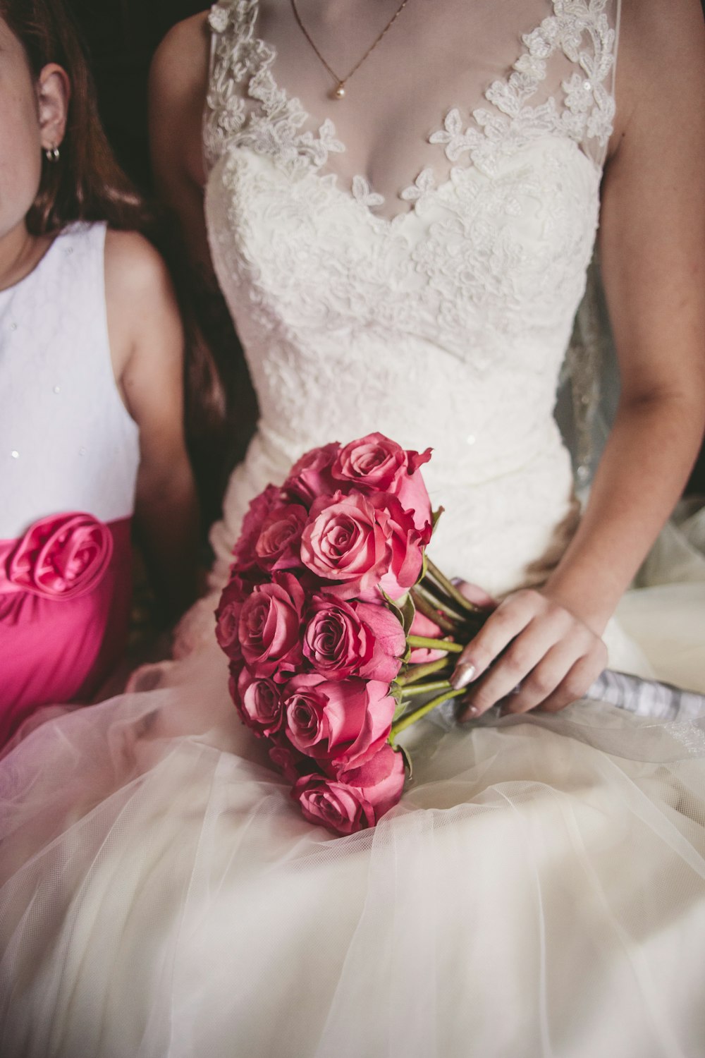 Femme portant une robe de mariée à fleurs blanche tenant un bouquet de rose