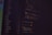A dark background with colorful lines of code in various programming languages displayed on a screen. The text includes snippets of functions and logical statements.