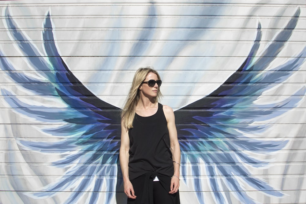 woman taking photo near wings painted wall