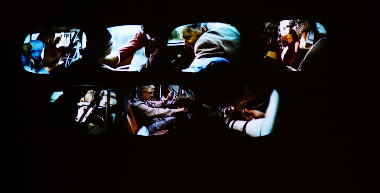 Multiple car interiors are visible, each showing different people engaged in various activities, including driving and handling objects. The scene appears dynamic and action-oriented.