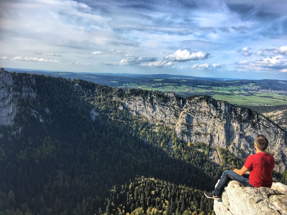 man sitting on brown rock during daytime