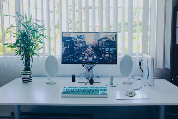 black flat screen computer monitor; keyboard; speakers; mouse on desk
