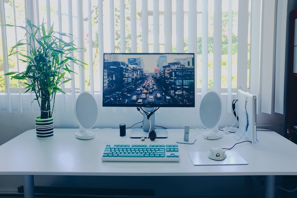 monitor de computador de tela plana preta; teclado; falantes; mouse na mesa