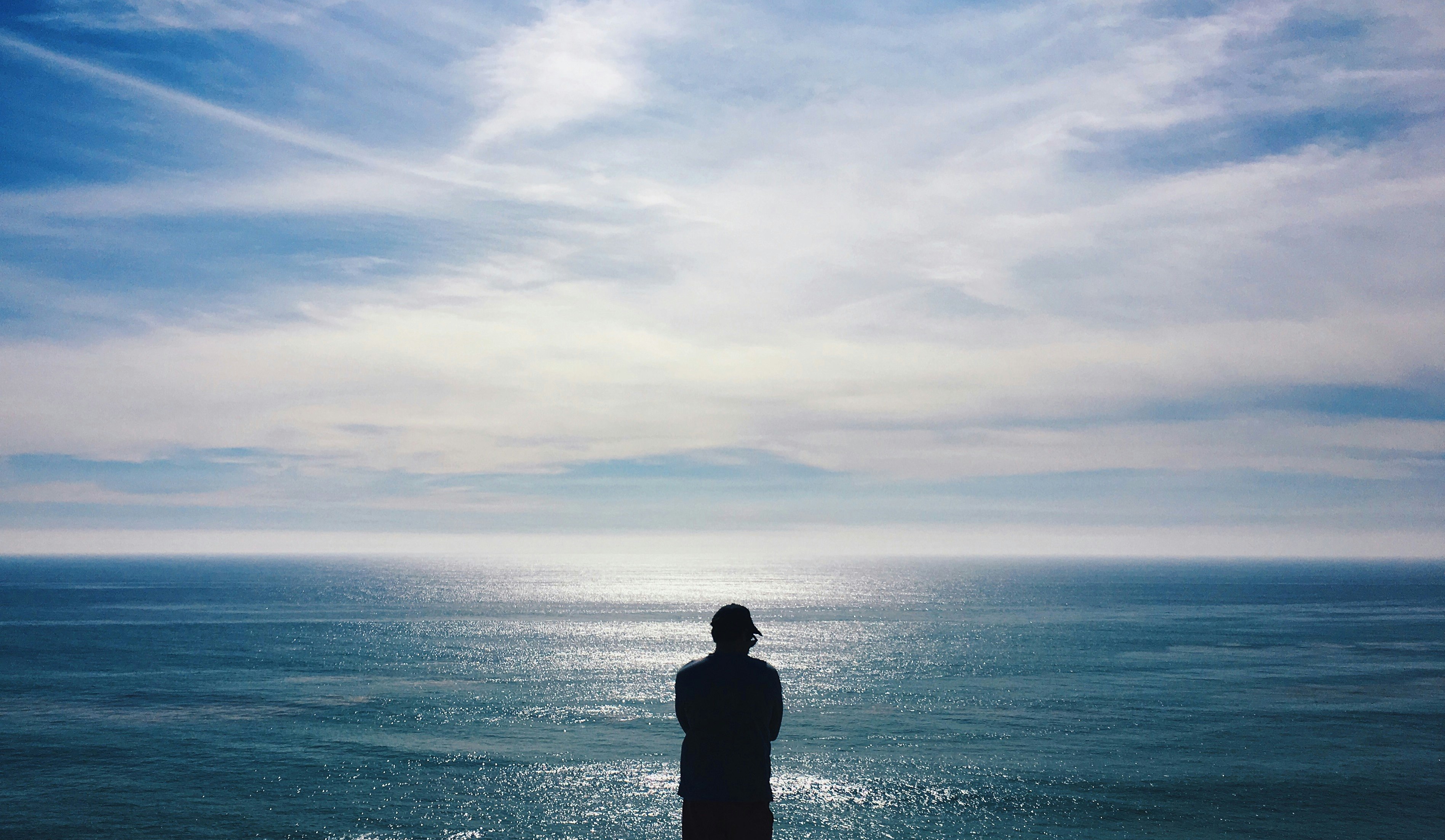 silhouette of man facing the sea