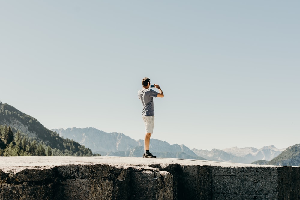 man standing on gray concrete cliff