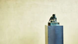 A vintage miniature sculpture from the 1950s displayed on a simple wooden stand.