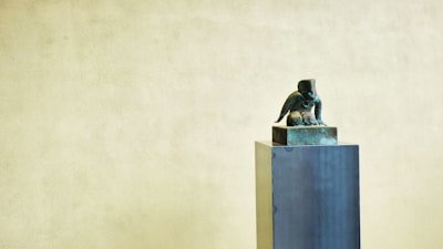 A bronze sculpture casting displayed on a wooden pedestal.