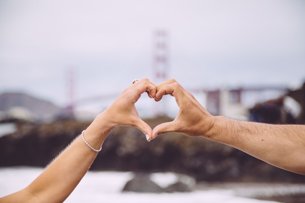 Coppia che forma il cuore usando le loro mani nella fotografia di messa a fuoco