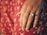 Close-up of a hand wearing a luxurious diamond ring on a velvet cushion.