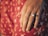Close-up of a hand wearing a luxurious diamond ring on a velvet cushion.