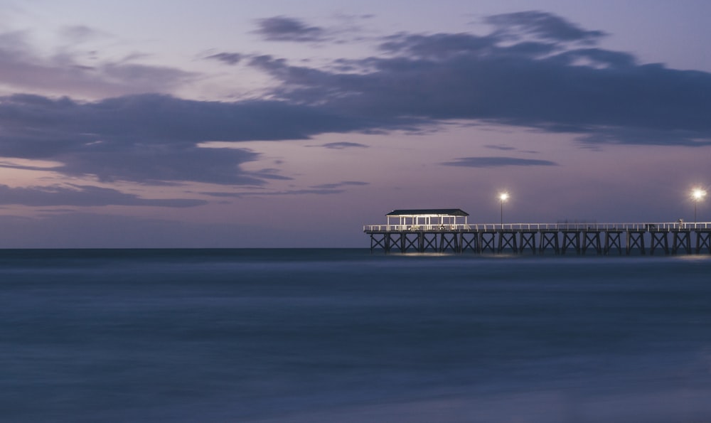 brown wooden shed on end of wooden dock in sea