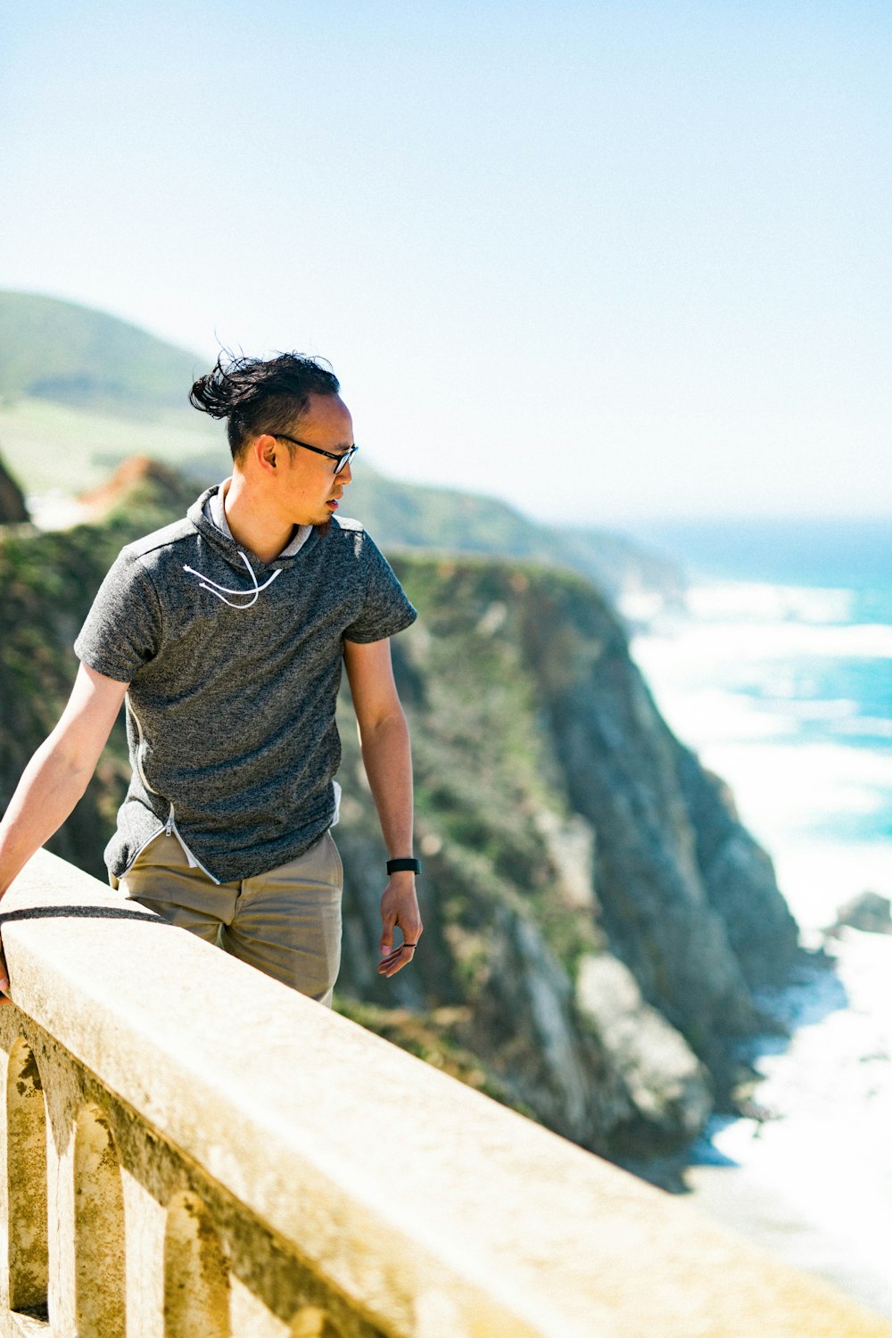 man standing on cliff while holding concrete barrier