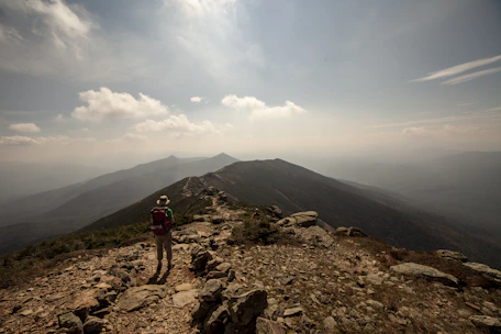 A scenic mountain trail with a lone hiker enjoying the sunrise, symbolizing adventure and discovery.