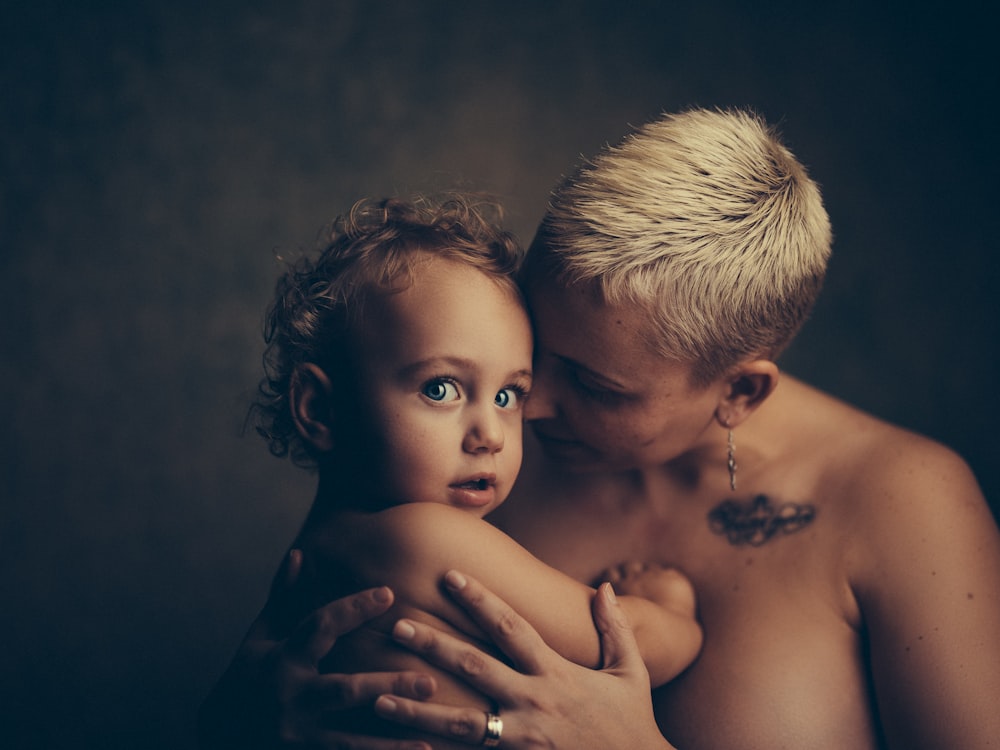mujer en topless sosteniendo a un bebé