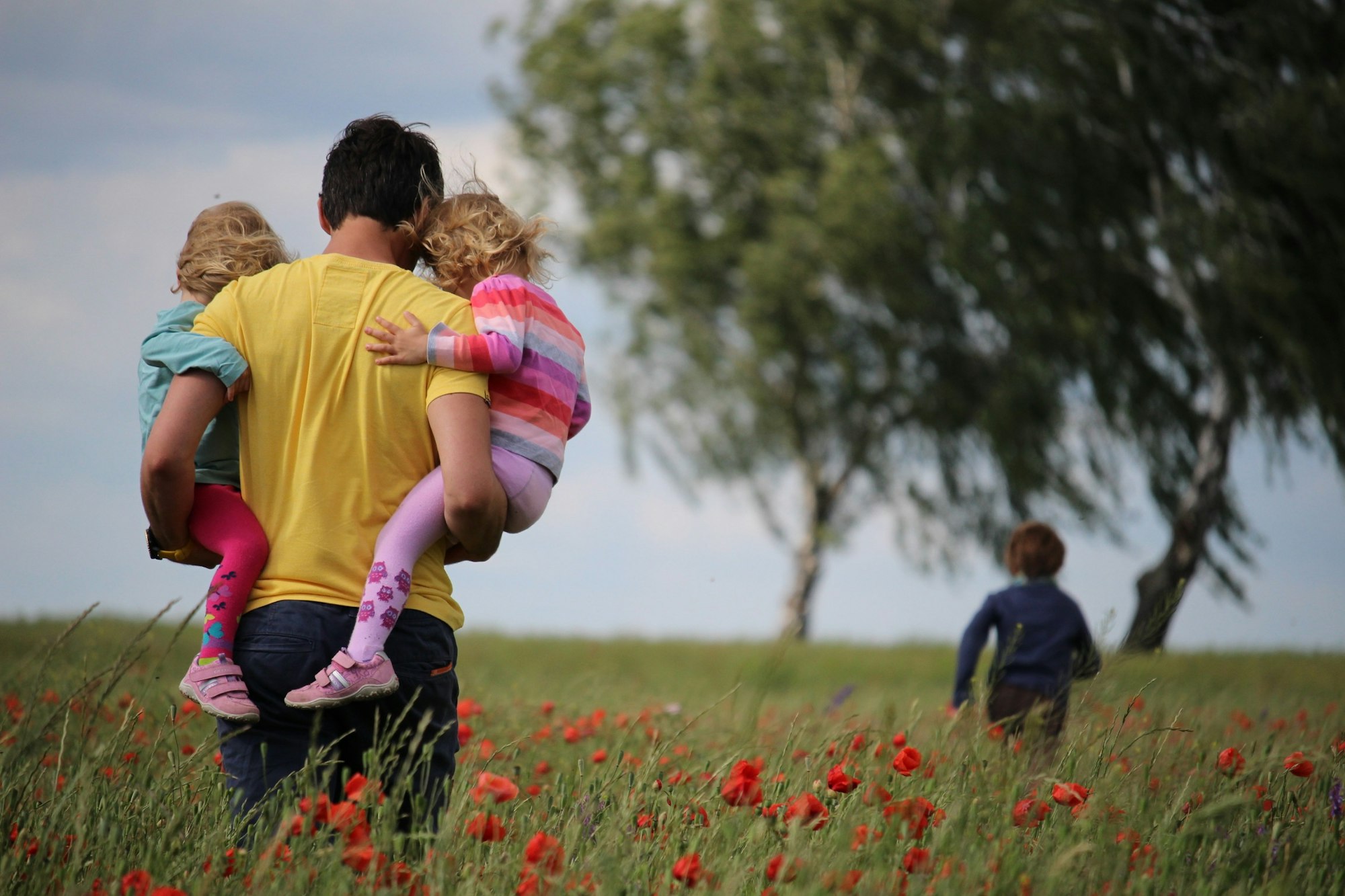 A family walking in the fields while the son leads.