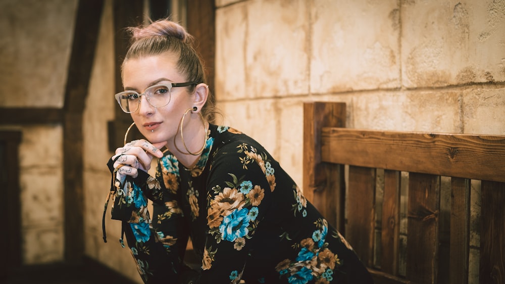 woman wearing black and multicolored floral long-sleeved dress taking photo beside bench inside the room