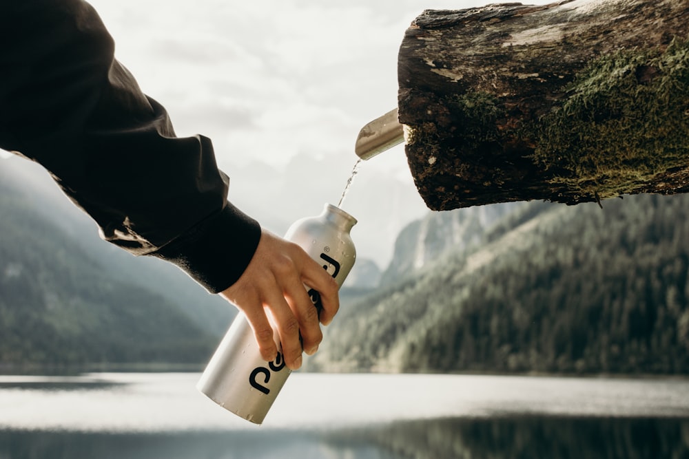 Persona sosteniendo una botella deportiva gris cerca de la boquilla