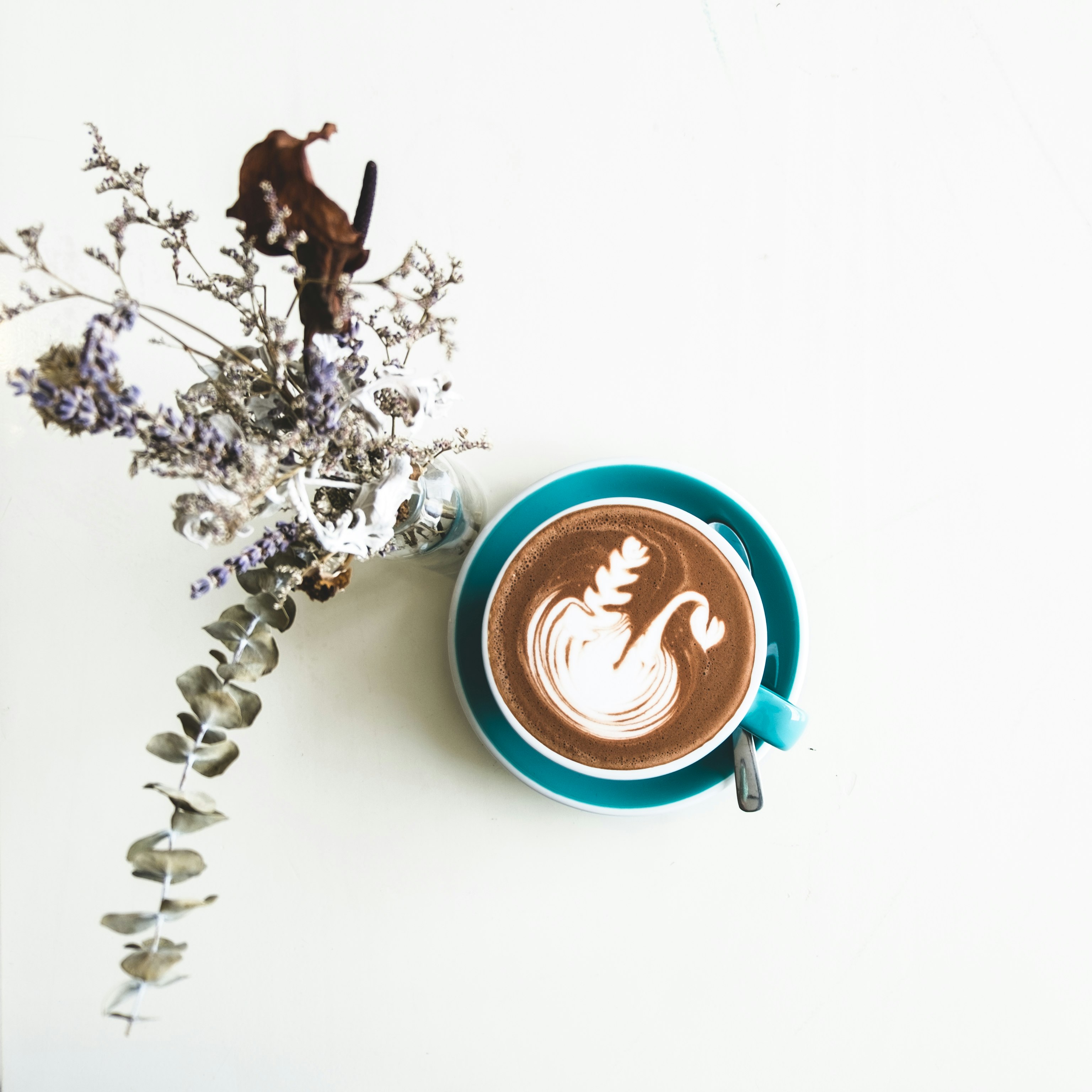 chocolate latte in cup beside flowers in vase