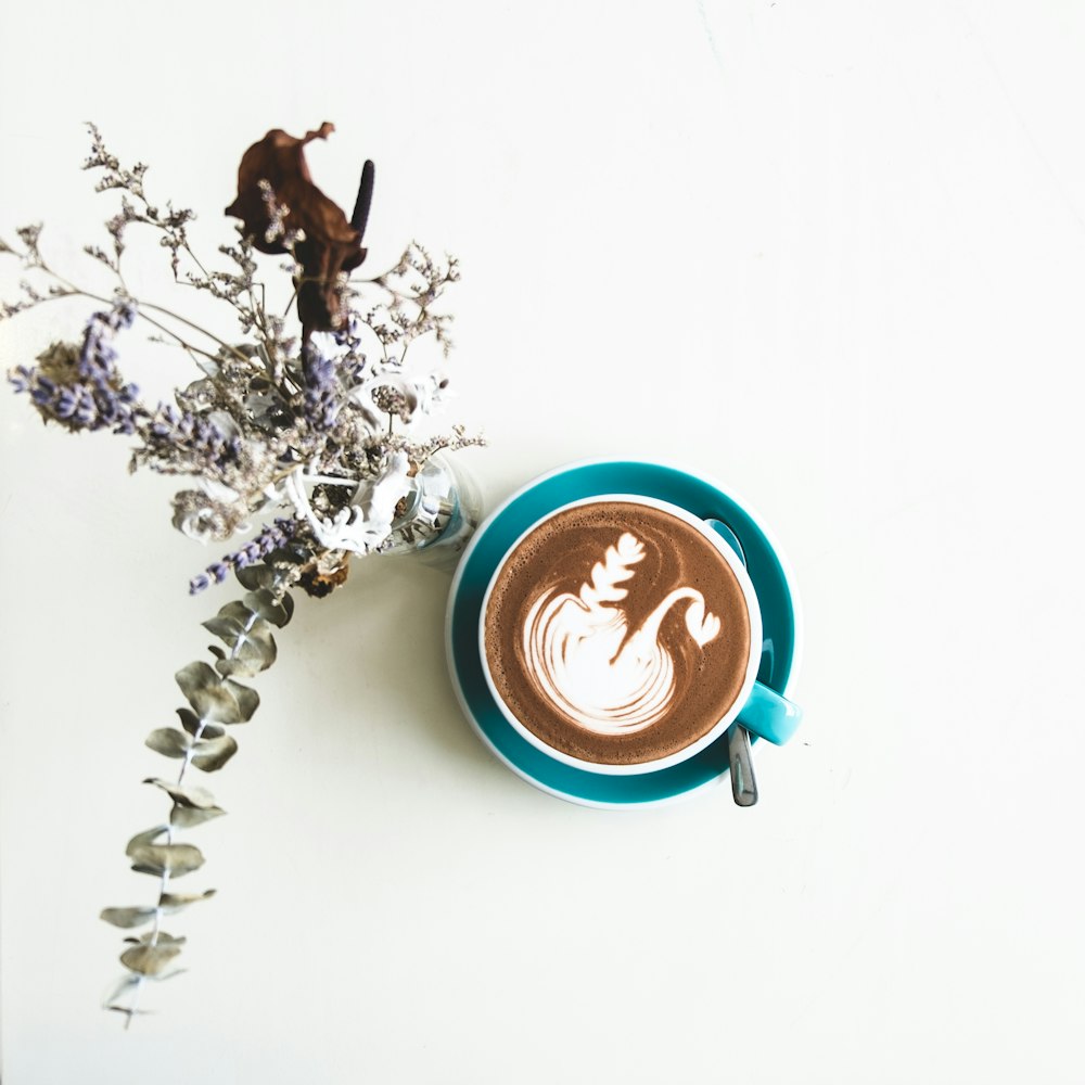 chocolate latte in cup beside flowers in vase