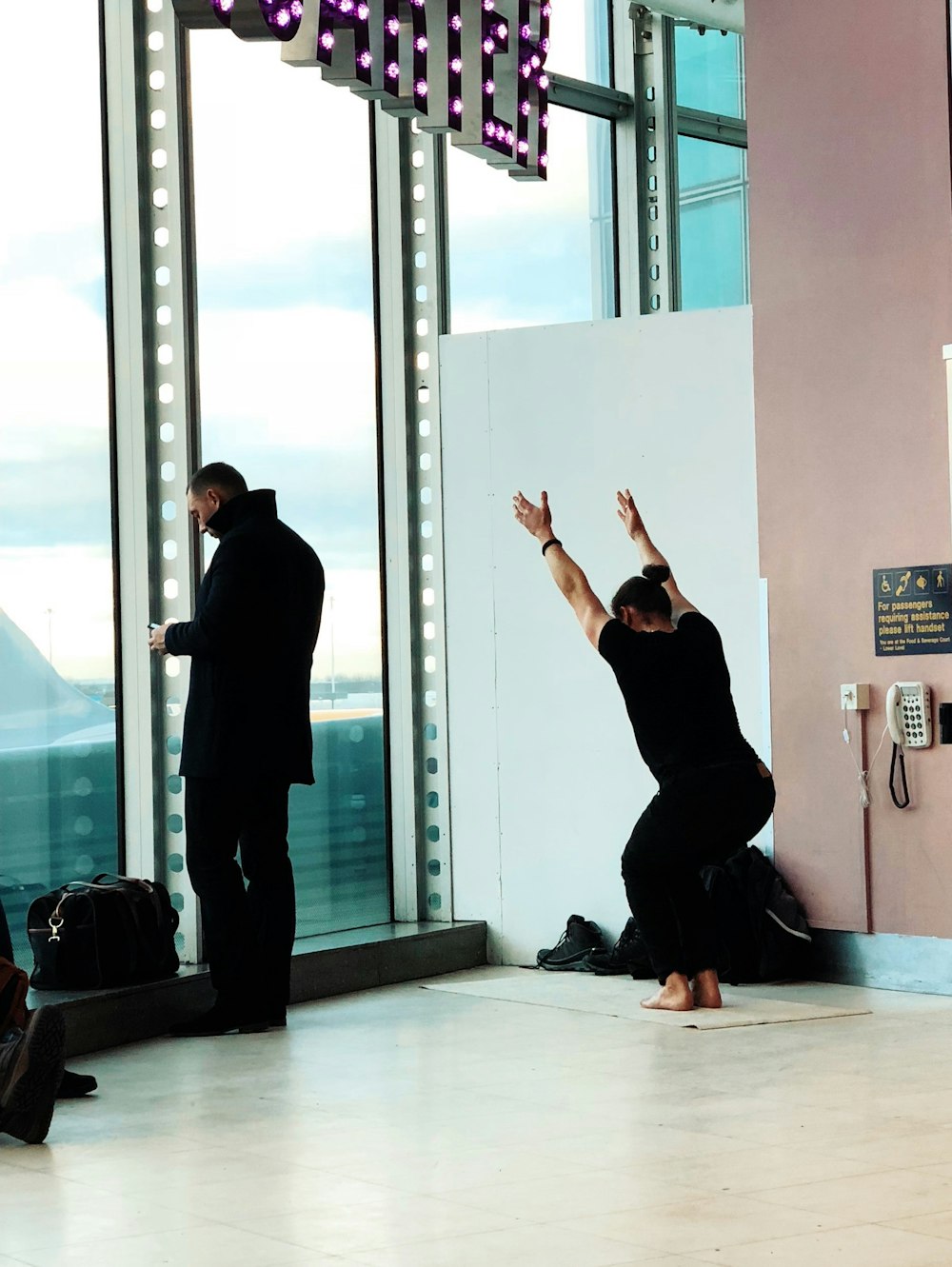 person squatting while raising his both arms upward in building