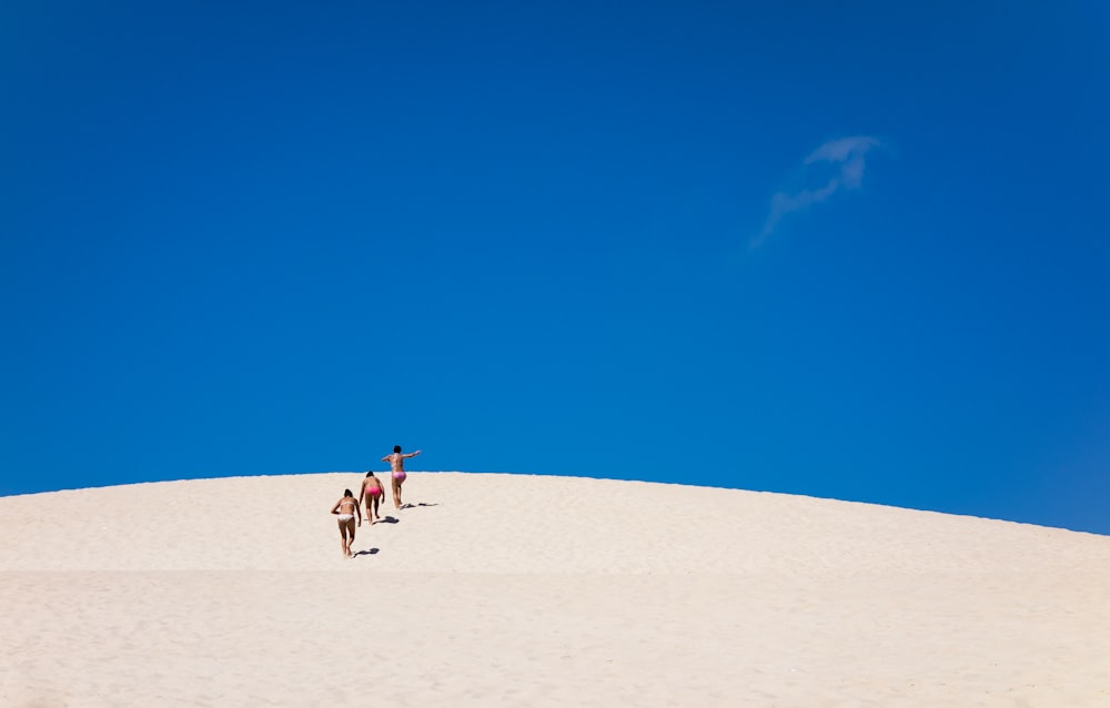 un groupe de personnes debout au sommet d’une colline de sable