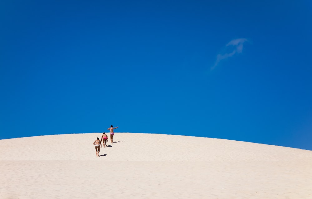 a group of people standing on top of a sandy hill