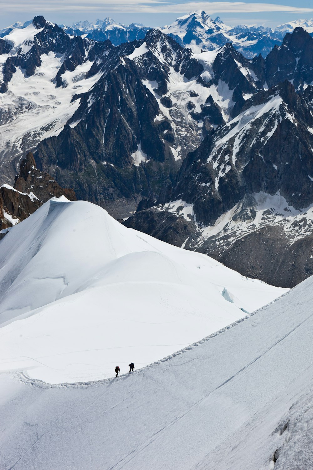 aerial view of two people hiking up snowy mountain