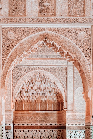 Intricately carved archways and walls feature traditional Islamic geometric patterns and floral motifs. The use of detailed arabesques and interlacing designs forms a stunning and harmonious display of craftsmanship.
