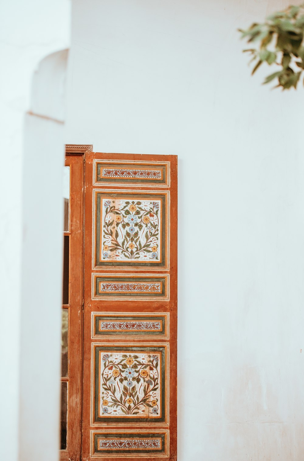 brauner und weißer Blumenholzschrank in der Nähe einer weißen Wand