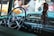 A classic car interior featuring a shiny chrome steering wheel with a Cadillac emblem, vintage dashboard with analog dials and switches. Hanging from the rearview mirror is a bundle of dried chilies, adding a distinctive touch.