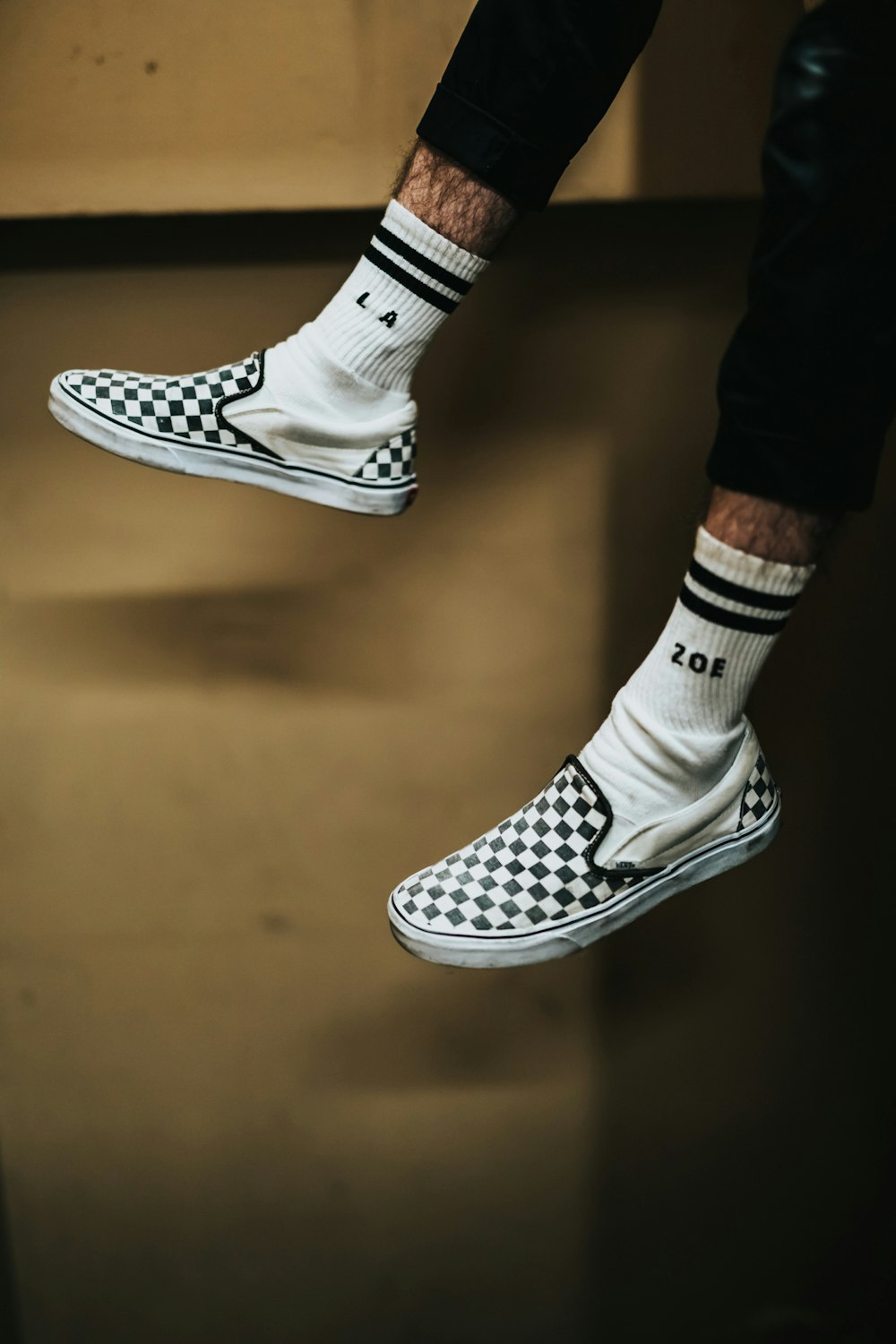 person wearing white-and-black checked slip-on shoes