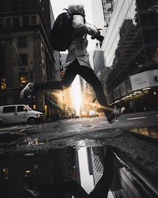 person jumping above puddle of water