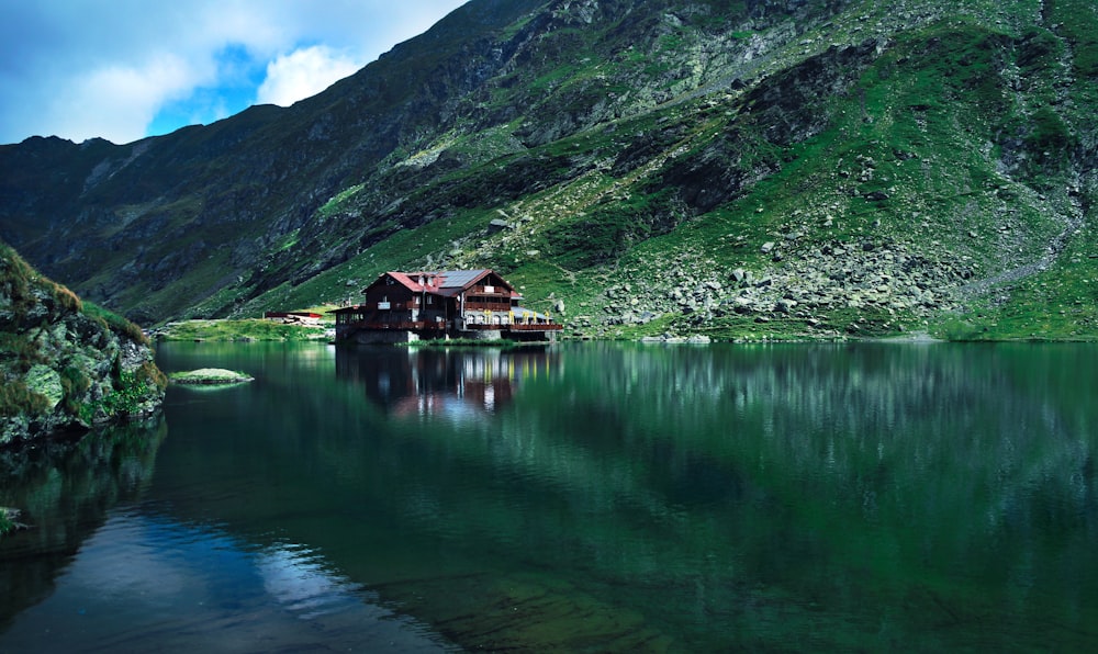 brown wooden house near mountain surrounded with water at daytime