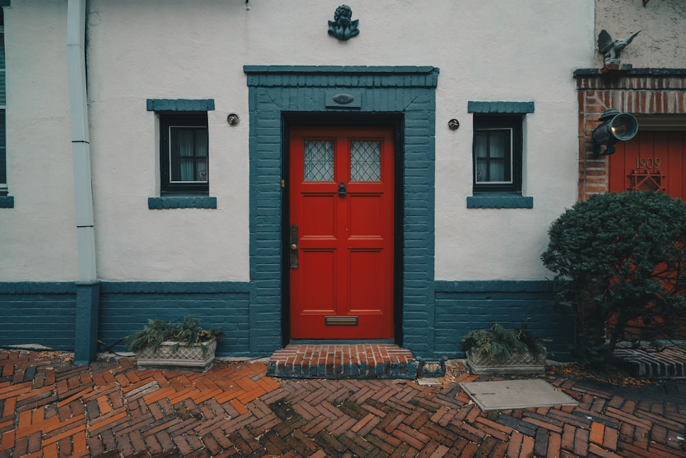 Porte en bois rouge sur maison en béton blanc et bleu
