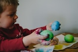 boy holding blue and green painted egg shells