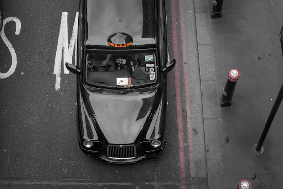 A sleek black taxi parked outside Winchester Cathedral on a sunny day.