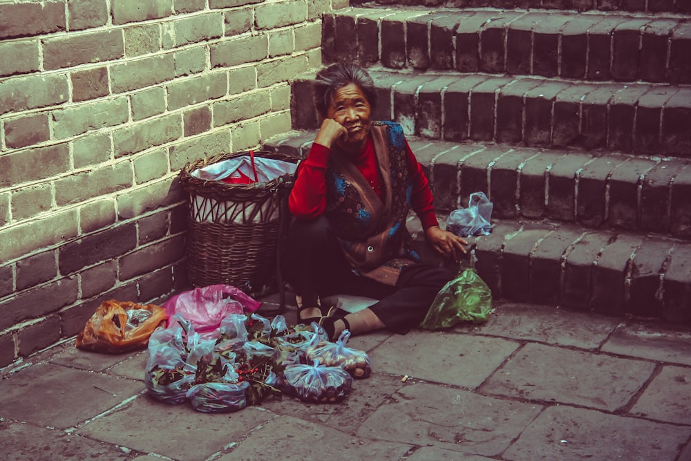 woman sitting on brown concrete ground beside brown wicker basket