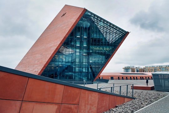 person standing in front of brown building in The Museum of Second World War Poland