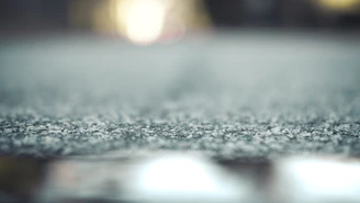 Low-angle shot of asphalt textures with motion blur and exhaust heat haze on a minimalist dark background.