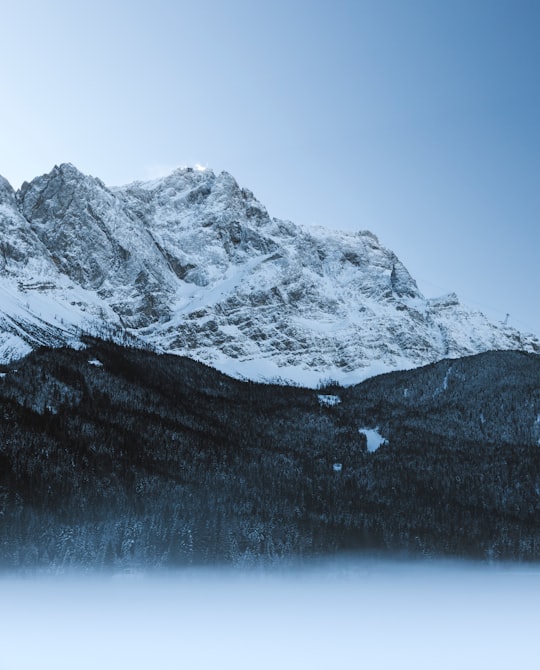 snow-covered mountain near trees under blue clear sky during daytime in Eibsee Germany